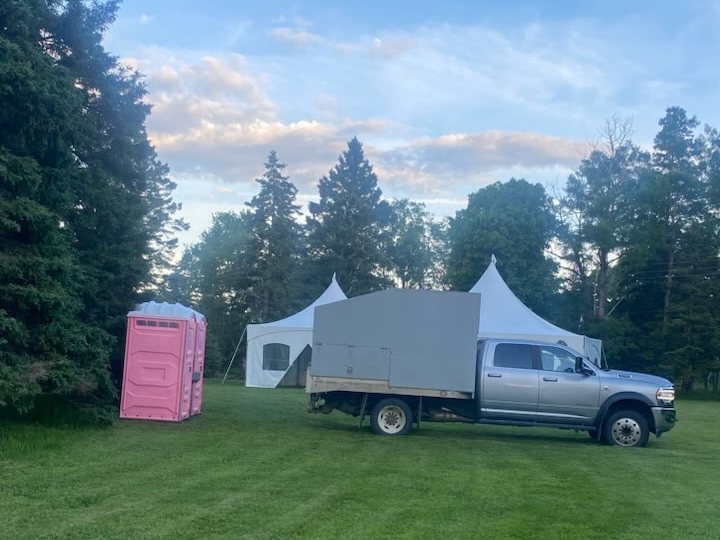 Pink portable toilets and a Stewart's service truck set up beside event tents